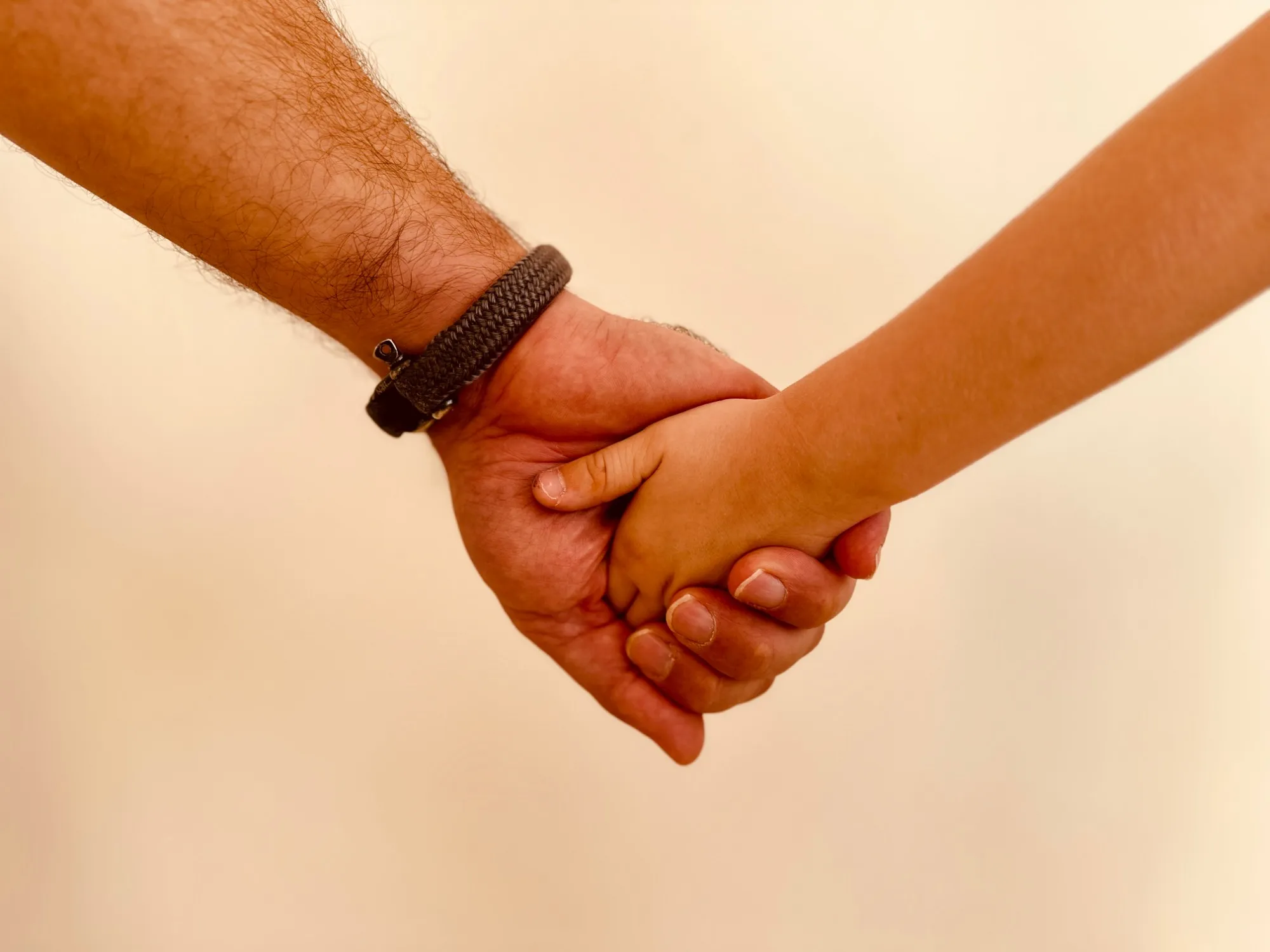 An adult’s hand holding a child’s hand